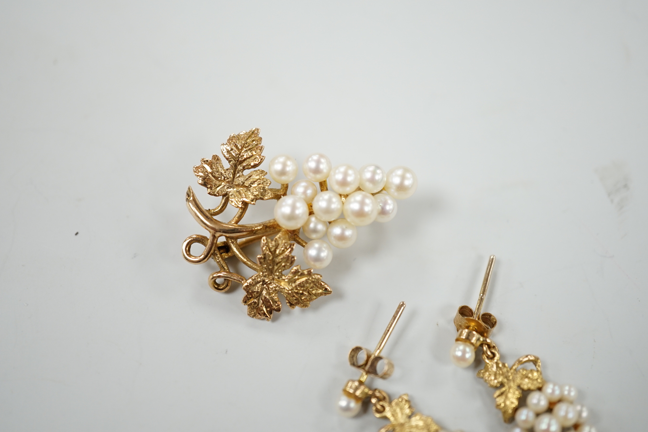 A modern 9ct gold and cultured pearl cluster set suite of jewellery, modelled as a bunch of grapes, comprising a brooch and pair of earrings, gross weight 7.3 grams.
